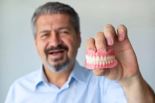 Patient holding a traditional denture