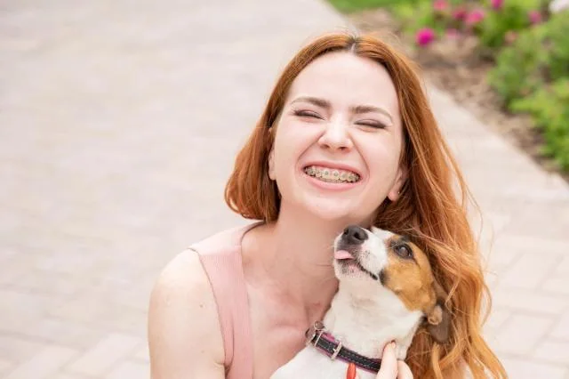 Optimum Dental orthodontic patient smiling with her dog